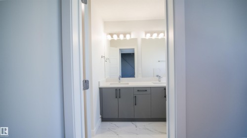 Bathroom featuring a double vanity with grey cabinetry, white countertops, and dual vessel sinks - 44 Dalquist Bay, Leduc, AB 
