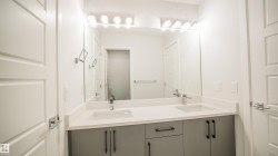 Modern double vanity featuring a light-toned countertop, dual integrated sinks, and contemporary gray cabinetry with black hardware - 