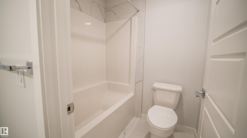 Bathroom featuring a tub/shower combination with white subway tile surround, white toilet, and polished chrome hardware - 44 Dalquist Bay, Leduc, AB 