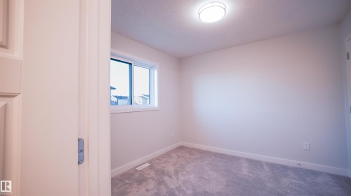 Bright room featuring a single window, overhead flush mount lighting, plush gray carpeting, and white baseboards - 44 Dalquist Bay, Leduc, AB 