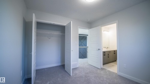 Light gray carpeted room featuring a bifold closet with wire shelving and a white vanity with gray cabinetry and modern hardware - 44 Dalquist Bay, Leduc, AB 