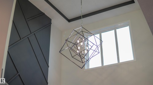 Geometric chandelier illuminating a high-ceiling space with a feature wall - 44 Dalquist Bay, Leduc, AB 