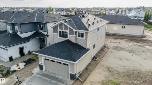 Contemporary two-story residence featuring light beige siding, a dark gray shingled roof, and an attached two-car garage - 44 Dalquist Bay, Leduc, AB 