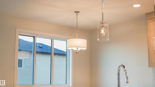 Window with white trim, a decorative pendant light, a modern pendant light, recessed lighting, and a chrome faucet - 44 Dalquist Bay, Leduc, AB 
