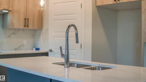 Kitchen island featuring a dual basin sink with a gooseneck faucet - 44 Dalquist Bay, Leduc, AB 
