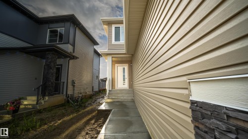 Contemporary exterior featuring tan horizontal siding and stacked stone accents - 44 Dalquist Bay, Leduc, AB 