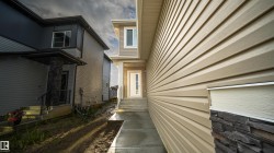 Contemporary exterior featuring tan horizontal siding and stacked stone accents - 