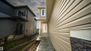 Contemporary exterior featuring tan horizontal siding and stacked stone accents - 44 Dalquist Bay, Leduc, AB 