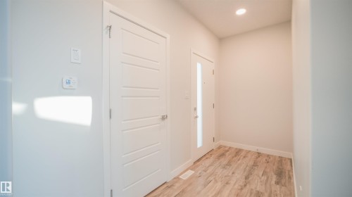 Entryway featuring wood-finish flooring, a modern panel door, and a thermostat - 44 Dalquist Bay, Leduc, AB 