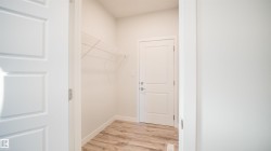 Utility room featuring a paneled door, wood-finish flooring, white baseboards, and wire shelving - 