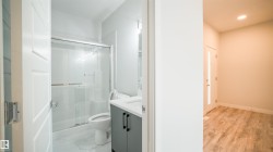 Bathroom featuring a glass-enclosed shower with a sliding door, a modern vanity with dark cabinetry, and a white countertop - 
