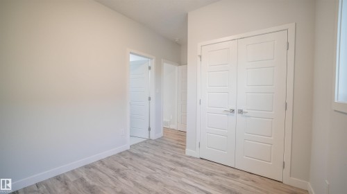 Neutral painted walls with white trim, featuring wood-finish flooring and modern panel doors - 44 Dalquist Bay, Leduc, AB 
