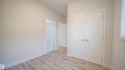 Neutral painted walls with white trim, featuring wood-finish flooring and modern panel doors - 