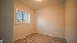 Room featuring light wood-finish flooring, neutral wall tones, and a window with white trim - 