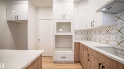 Modern kitchen featuring white upper cabinetry, wood-finish lower cabinetry, and light-toned countertops - 