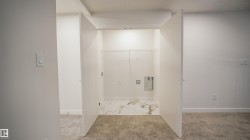 Dedicated laundry alcove with white marble-look flooring - 