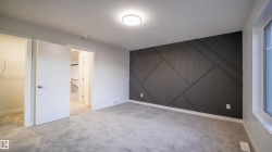 Bedroom featuring a dark accent wall with geometric paneling, light gray carpeting, a large window, and a flush-mount ceiling light - 