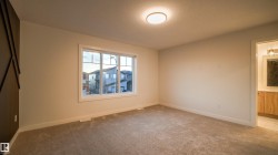 Spacious room featuring neutral carpet flooring, a large window with white trim, and a contemporary flush-mount ceiling light - 
