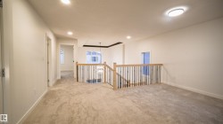 Spacious landing area featuring plush carpet flooring, recessed lighting, and a contemporary wood and wrought iron railing - 
