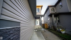 Contemporary exterior featuring light beige horizontal siding, dark gray horizontal siding, and dark stacked stone accents - 
