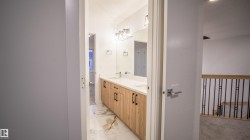 Bathroom featuring a double vanity with wood-finish cabinetry, white countertops, and dual wall-mounted mirrors - 