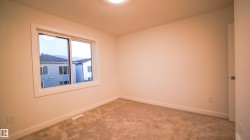 Comfortable room featuring a white-framed window, neutral carpeting, and a flush-mounted ceiling light - 