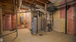Unfinished basement with concrete flooring, exposed wood framing, and visible insulation - 