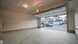 Spacious garage featuring a concrete floor, exposed drywall walls, and an automatic overhead door opener - 