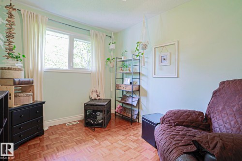 Light-filled room featuring a double window, wood-finish parquet flooring, light green wall paint, white baseboards, and a textured ceiling - 2007 67 Street, Edmonton, AB 
