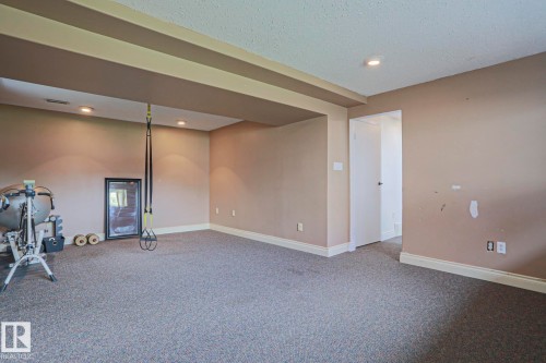 Spacious interior room featuring neutral-toned walls, recessed lighting, gray carpeting, and white baseboards - 2007 67 Street, Edmonton, AB 
