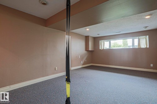 Spacious room featuring neutral-toned walls, recessed lighting, and a large horizontal window - 2007 67 Street, Edmonton, AB 