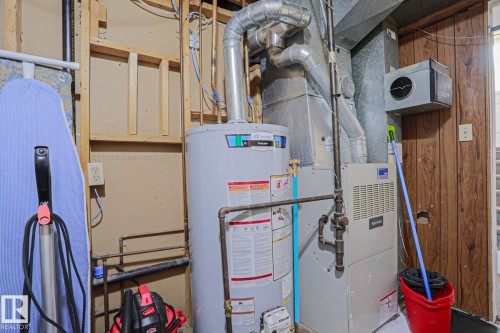 Utility area featuring a water heater, furnace, exposed wall studs, and wood paneling - 2007 67 Street, Edmonton, AB 