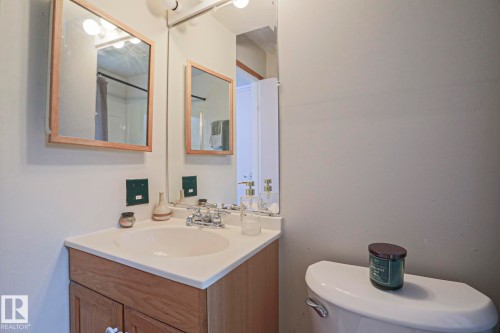 Bathroom vanity with a light wood-finish cabinet, white countertop, and integrated sink - 2007 67 Street, Edmonton, AB 