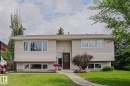 Split-level residence featuring a brown entry door, neutral siding, white window frames, and a brown shingle roof - 2007 67 Street, Edmonton, AB 