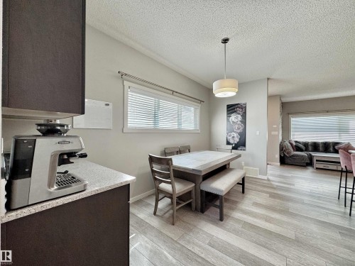 Dining area featuring light wood-finish flooring, a contemporary pendant light fixture, and a window with horizontal blinds - 302 Balsam Link, Leduc, AB 