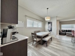 Dining area featuring light wood-finish flooring, a contemporary pendant light fixture, and a window with horizontal blinds - 