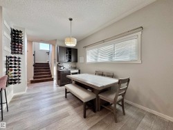 Dining area featuring wood-finish flooring and a built-in beverage station with dark cabinetry - 