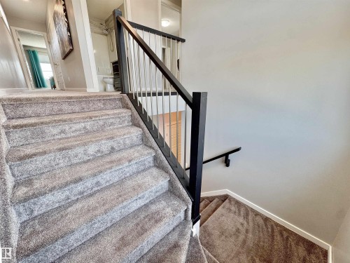Carpeted staircase featuring a contemporary black and silver metal railing system - 302 Balsam Link, Leduc, AB 