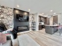 Open-concept living area featuring wood-finish flooring, recessed lighting, and a kitchen with dark wood cabinetry - 302 Balsam Link, Leduc, AB 
