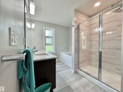 Contemporary bathroom featuring a spacious glass-enclosed shower with tile surround, double vanity with granite countertop, built-in soaking tub, and tile flooring - 