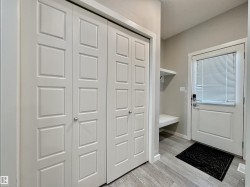 Entryway featuring light wood-finish flooring and a white paneled door with integrated blinds - 