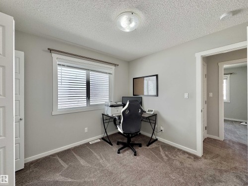 Versatile room featuring light gray walls, textured ceiling, a window with horizontal blinds, and neutral-toned carpeting - 302 Balsam Link, Leduc, AB 