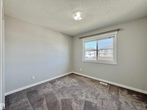 Carpeted room featuring light gray painted walls, a flush-mount ceiling light fixture, a window with white trim, and a window treatment - 302 Balsam Link, Leduc, AB 