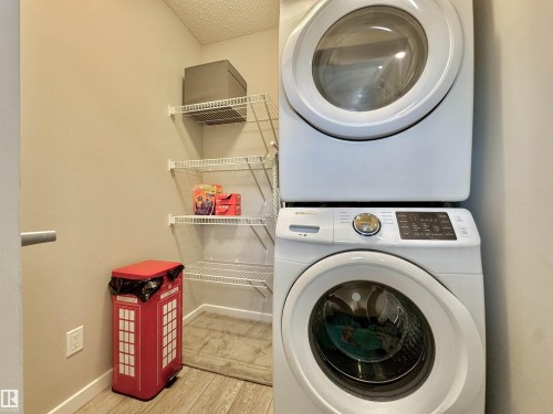 Dedicated laundry area featuring a white stackable washer and dryer unit, wire shelving, and wood-finish flooring - 302 Balsam Link, Leduc, AB 
