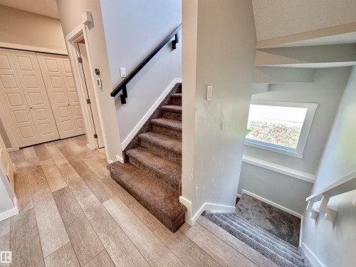 Carpeted staircase with dark handrail - 302 Balsam Link, Leduc, AB 