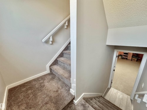 Carpeted staircase with white trim and a coordinating handrail - 302 Balsam Link, Leduc, AB 