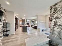 Open-concept living area featuring light wood-finish flooring, recessed ceiling lighting, and a kitchen with dark cabinetry - 