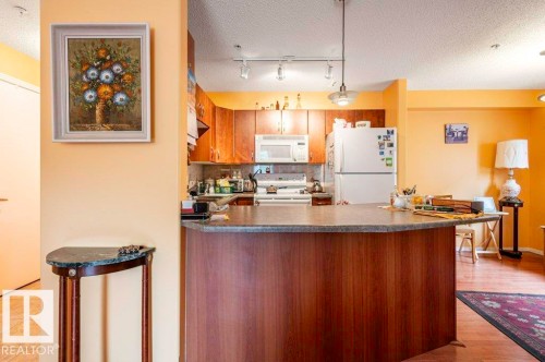 Kitchen featuring lots cabinetry, white appliances, a eat-up bar and plenty of counter space - 303 10528 77 Avenue, Edmonton, AB 