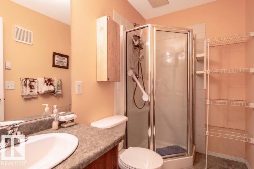 Main Bathroom featuring a glass-enclosed shower, a vanity with an integrated sink and laminate countertop, and a wall-mounted cabinet - 303 10528 77 Avenue, Edmonton, AB 