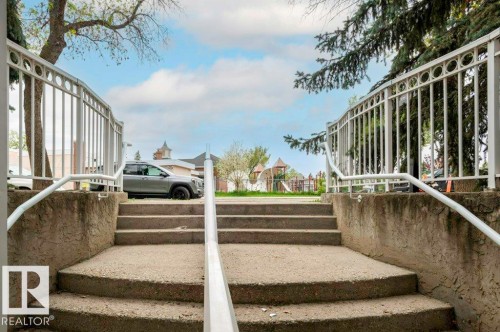 Concrete exterior staircase with white metal railings - 303 10528 77 Avenue, Edmonton, AB 